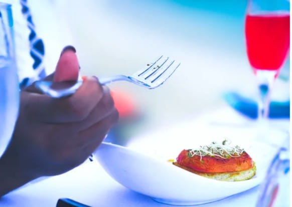Blue-toned close-up of food being cooked with a fork