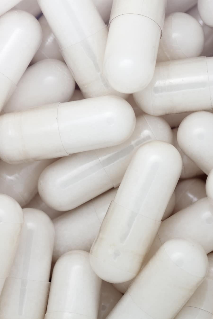 White glucosamine capsules spilling from a supplement bottle