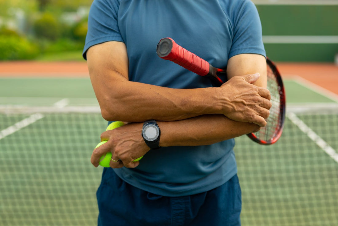 Tennis player on a court holding their forearm near the elbow