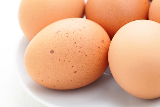 Fresh eggs grouped together on a plain background