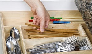 Person organizing utensils in a kitchen drawer