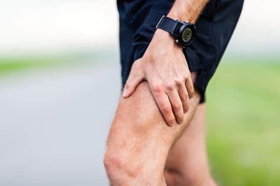 Runner in athletic wear gripping their lower leg during training