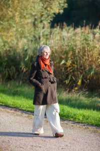 Senior woman walking along a path in a green park