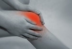 Close-up of a person holding their knee with both hands